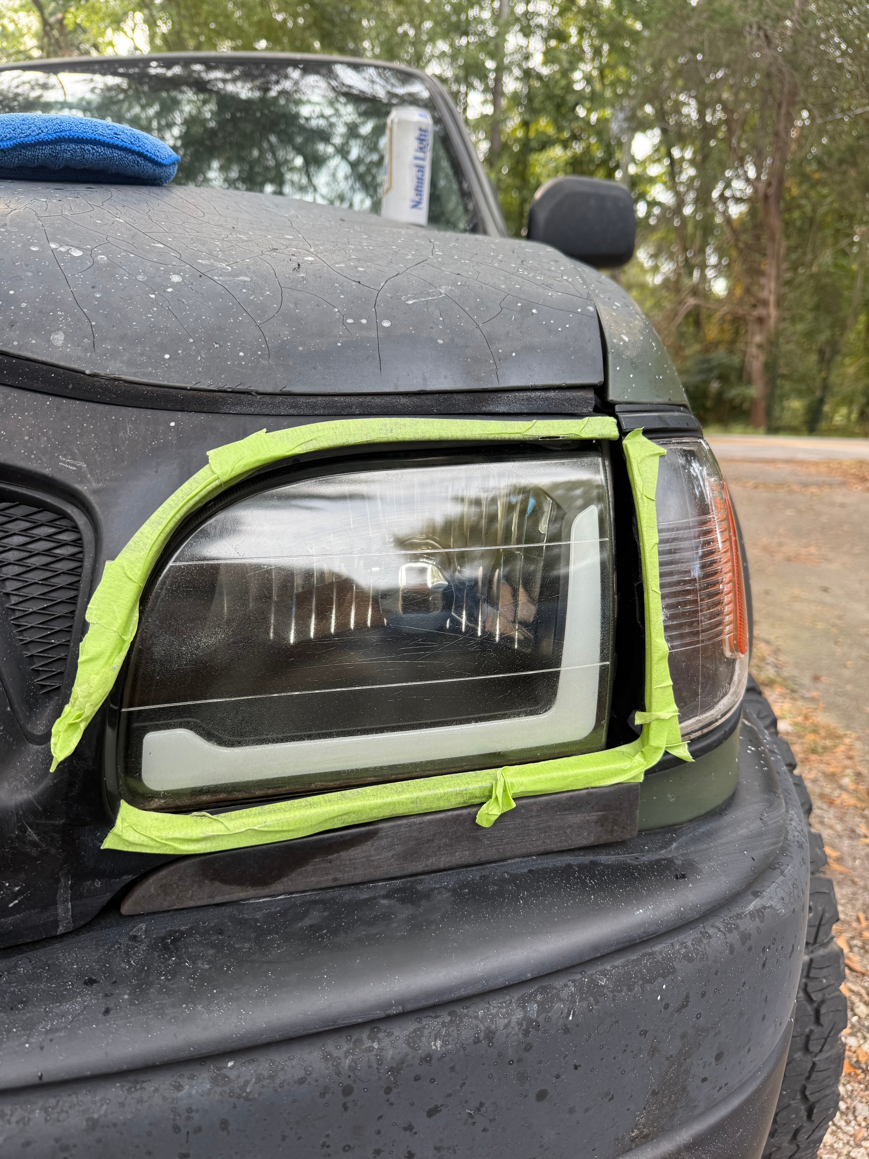 Dark truck headlight taped and mid-restoration process